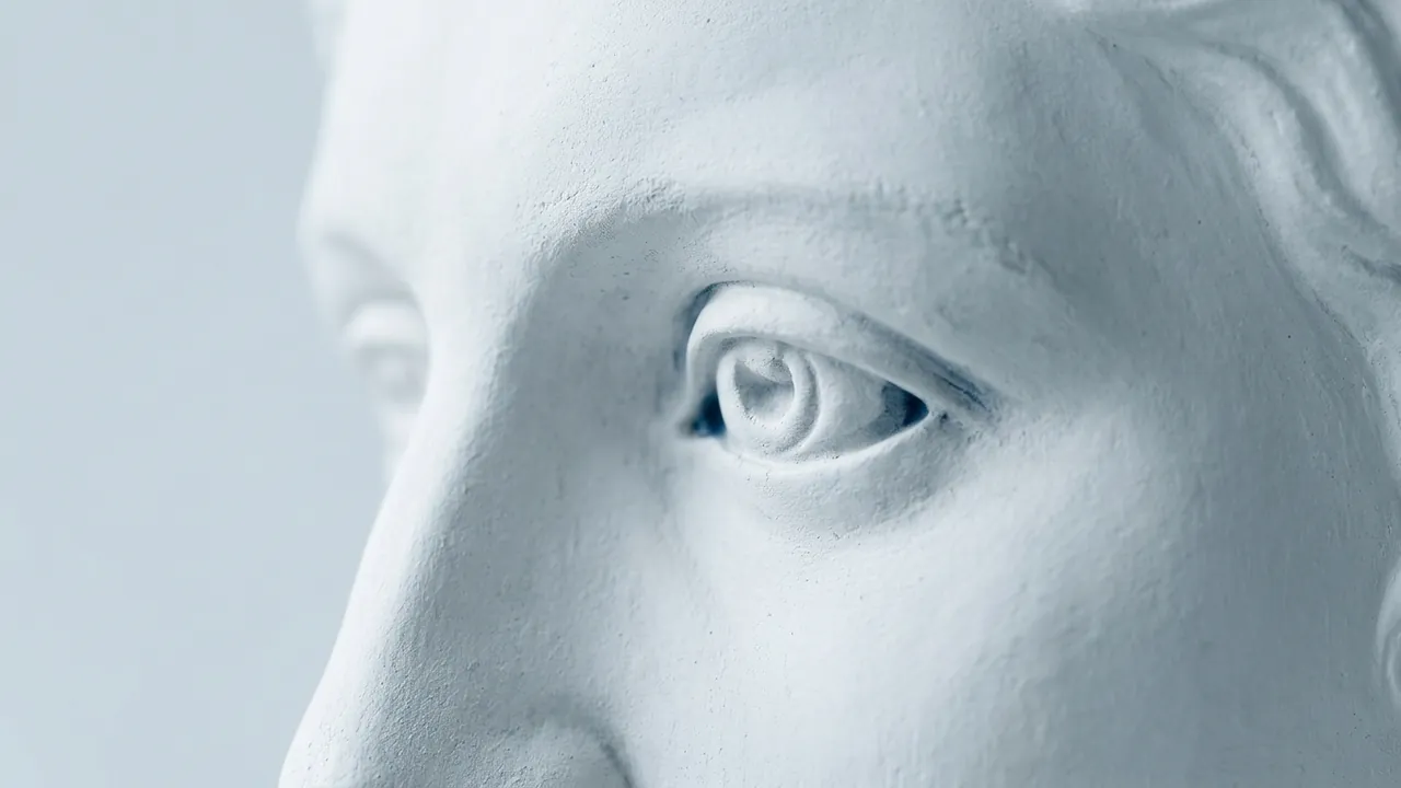 A very close view of a white plaster statue's carved eye and temple, its outer corner lifted — fox eye surgery guide